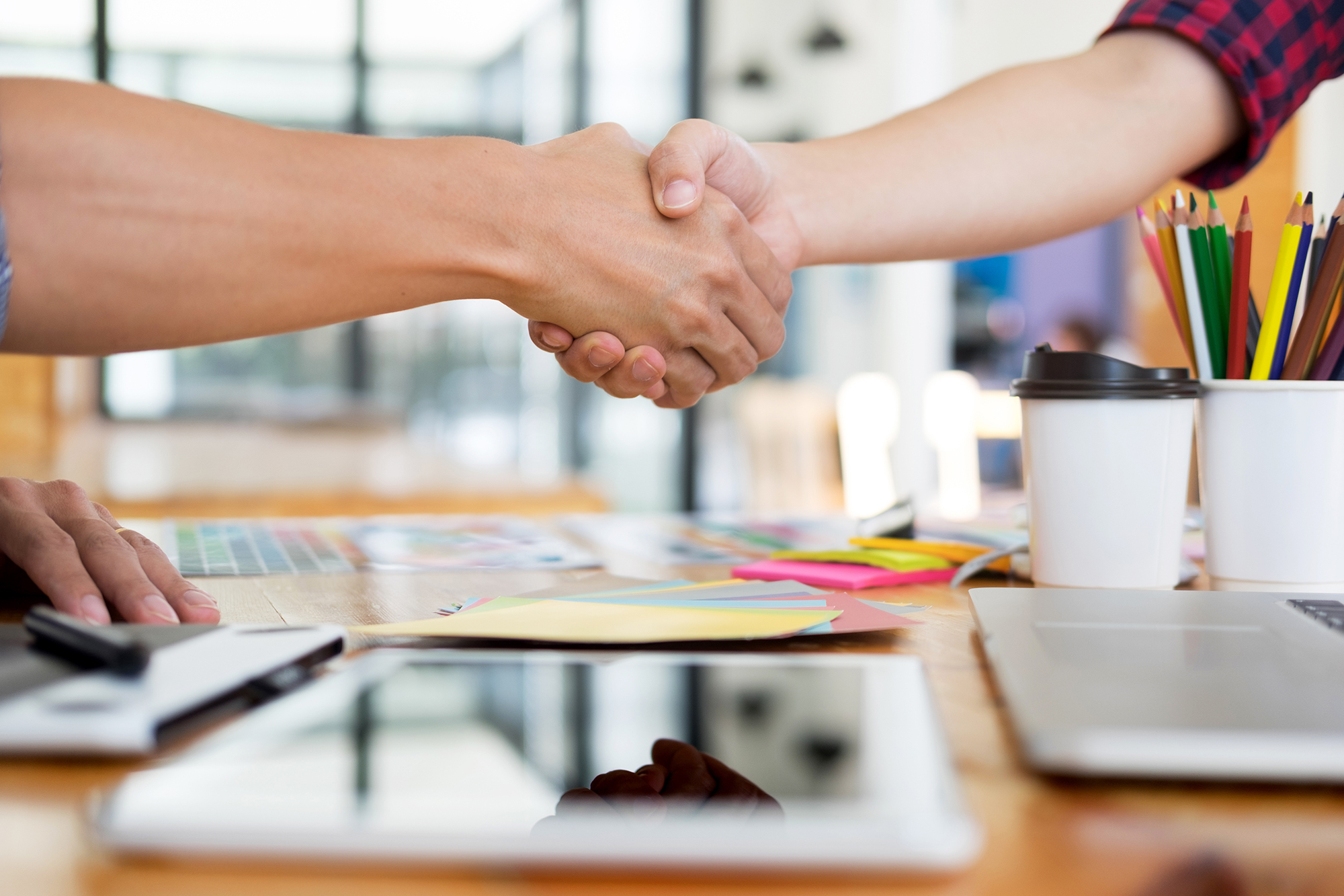 Two business partners shaking hands at a work table